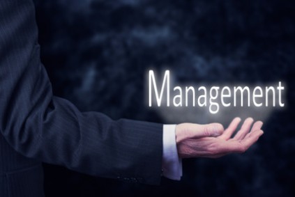 The arm of a businessman holding the word Management.